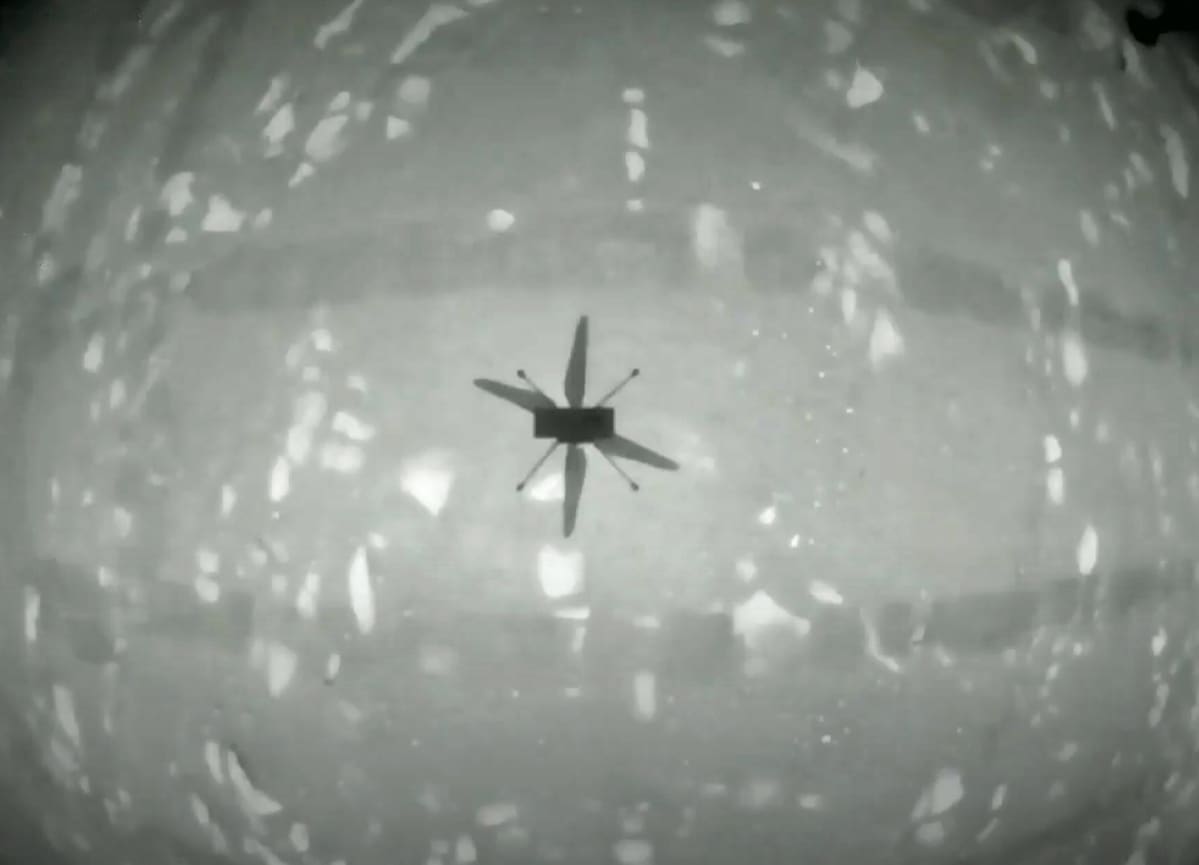 Mustavalkoinen kuva pienen helikopterin varjosta kaarevalla pinnalla.