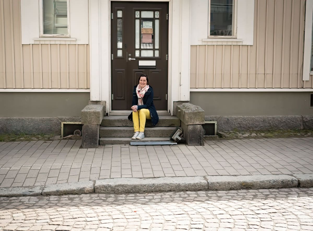Kakkumestari Jenni Höijer istuu kahvilansa rappusilla.