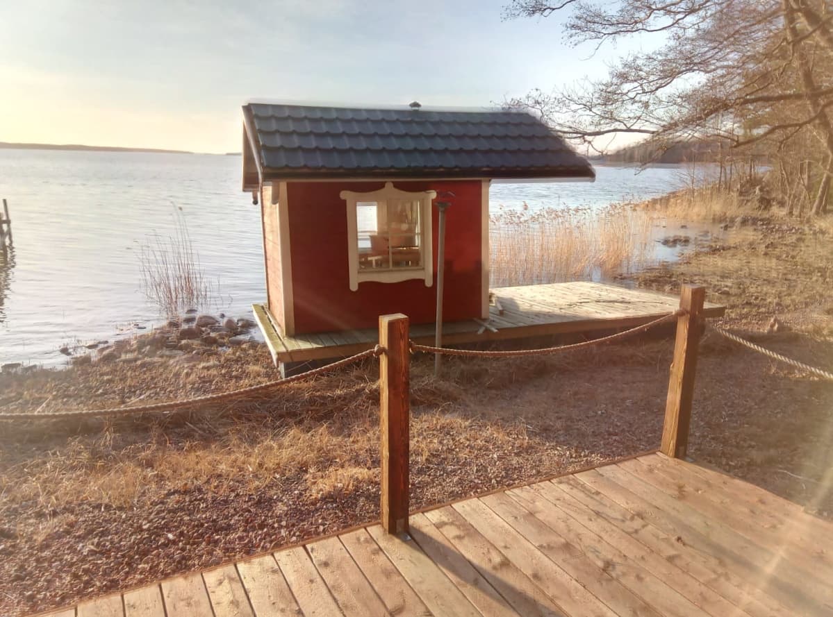 Punainen saunalautta rannalla.