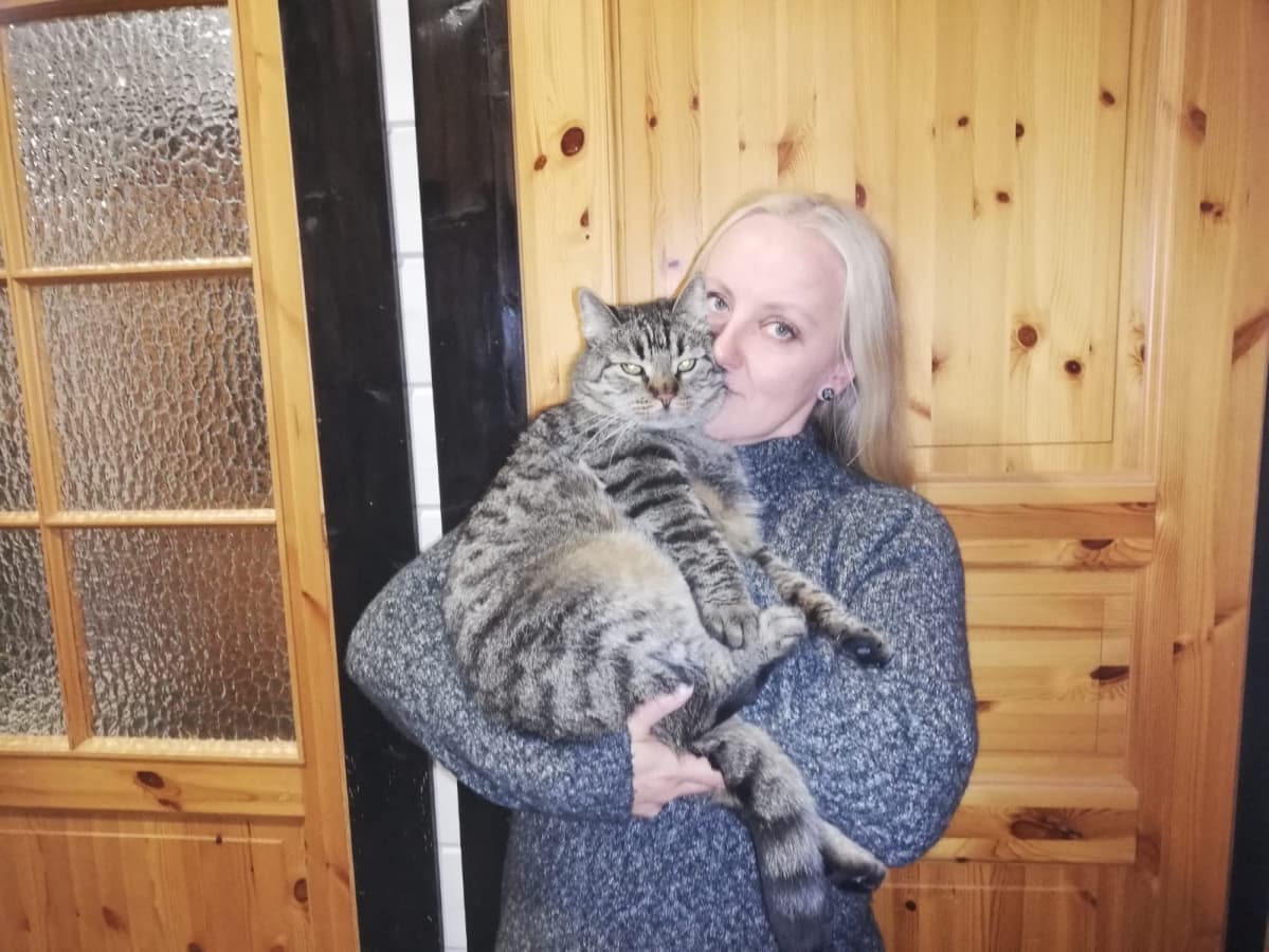 Nainen pitää kissaa sylissään