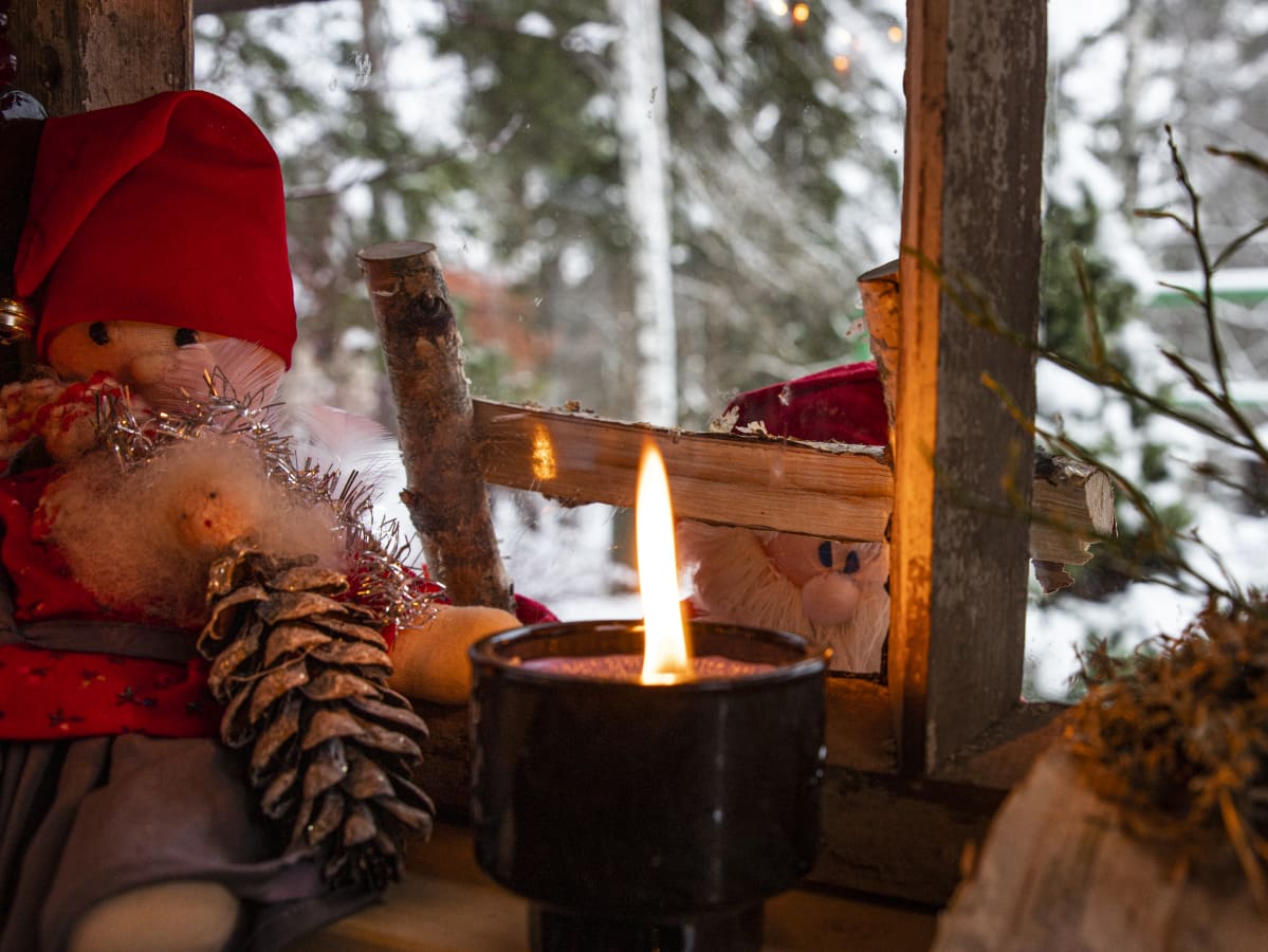 Tonttu kurkkaamassa ikkunasta mökkiin.