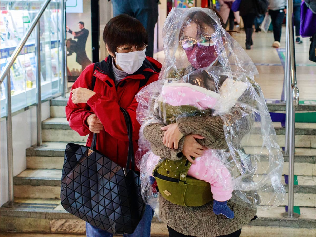 Nainen on suojannut itsensä ja lapsensa läpinäkyvällä sadeviitalla Hongkongissa.