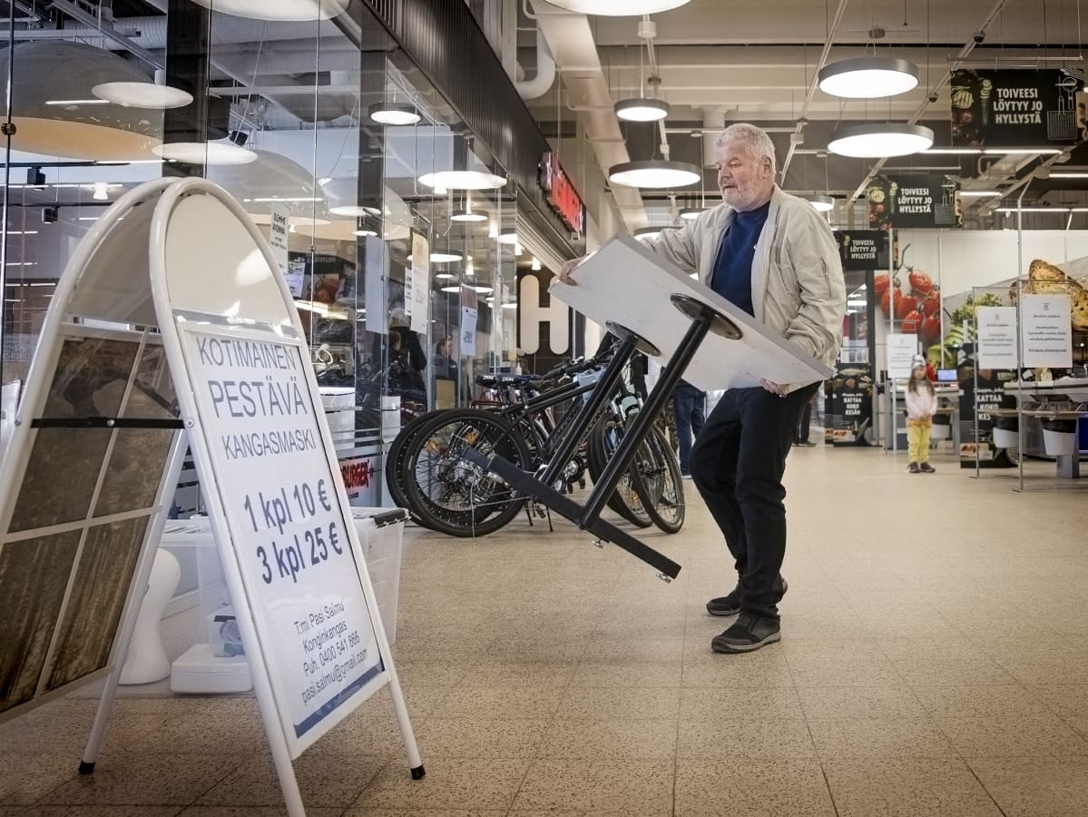 Pasi Salmu kantaa pöytää kauppakeskuksen käytävällä.