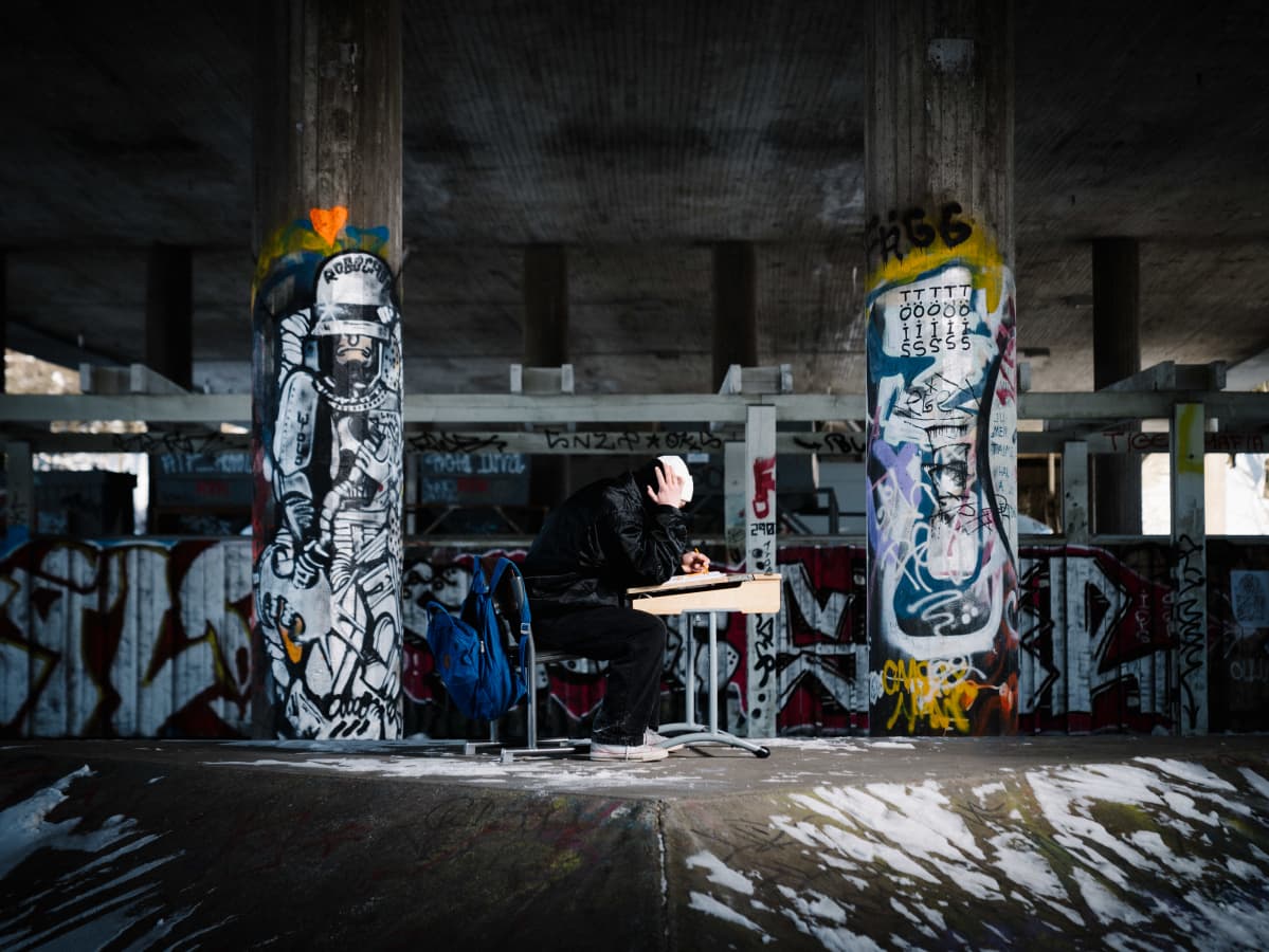 kuvituskuva nuori istuu yksin pulpetin ääressä graffitien ympäröimänä
