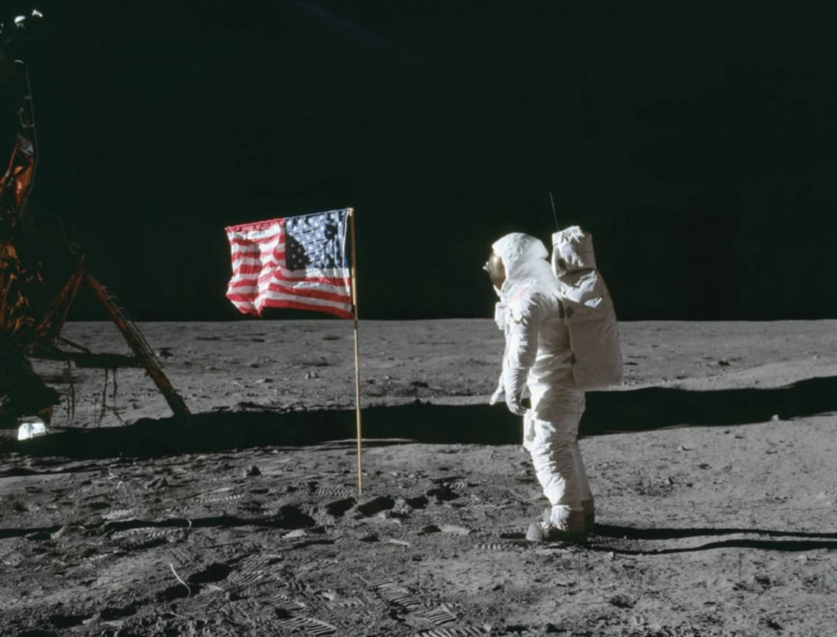 Astronautti ja lippu Kuun pinnalla, laidassa näkyy hieman Eagle-laskeutujaa.