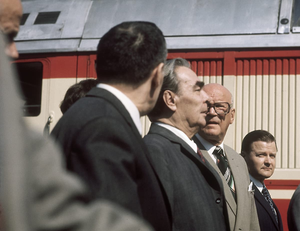 Neuvostoliiton Kommunistisen puolueen pääsihteeri Leonid Brezhnev Helsingin rautatieasemalla saapumassa ETY-kokoukseen 1. elokuuta 1975. Brezhnevin profiilin takana presidentti Urho Kekkonen ja tainpana pääministeri Keijo Liinamaa. Edessä oleva takaraivo lienee Neuvostoliiton ulkoministeri Andrei Gromykon.