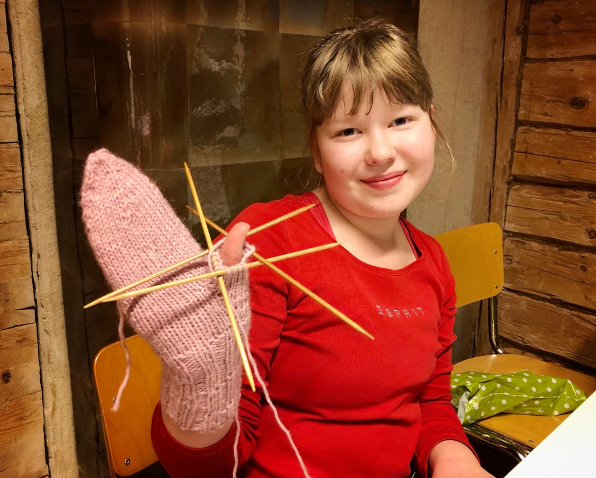 Hanna Hömmä esittelee ensimmäistä, vaaleanpunaiseen lapaseen neulomaansa peukaloa.