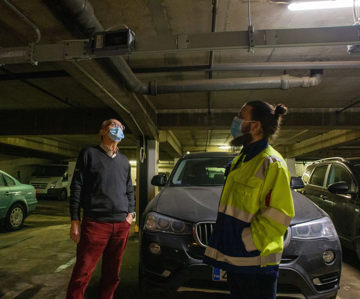 Timo Viljamaa, taloyhtiön puheenjohtaja ja Tatu Vattulainen, työnjohtaja, katsovat sähkönjohtoja vievää palkkia parkkihallin katossa.