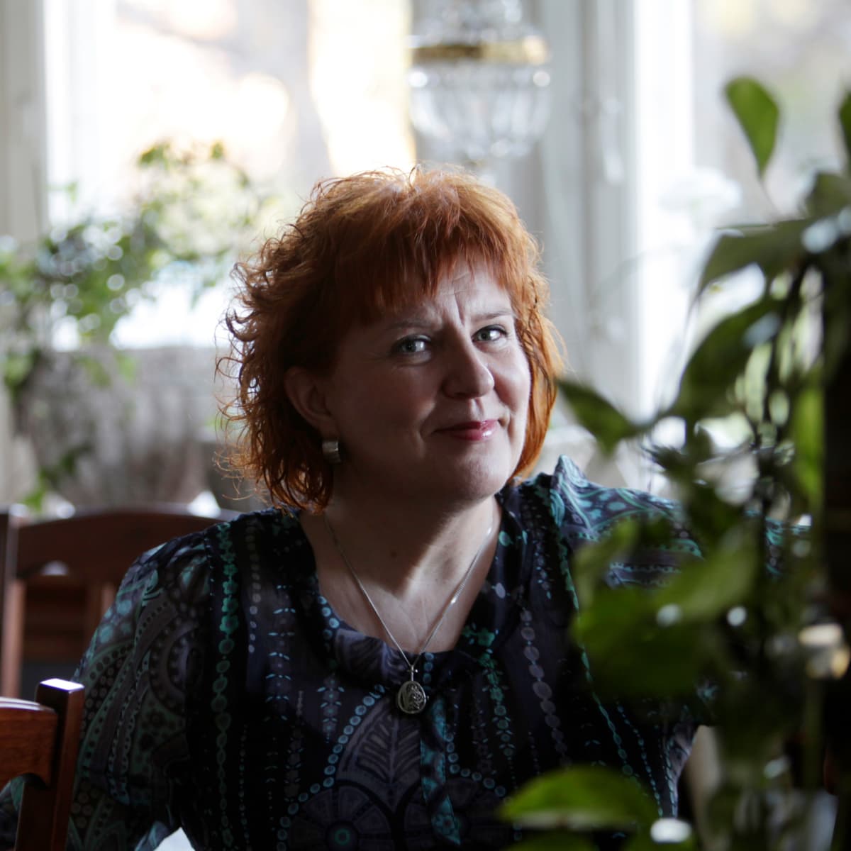 Väestöliiton terapiapalvelujen vastaava psykoterapeutti Tarja Santalahti istuu pöydän ääressä ja katsoo kameraan.
