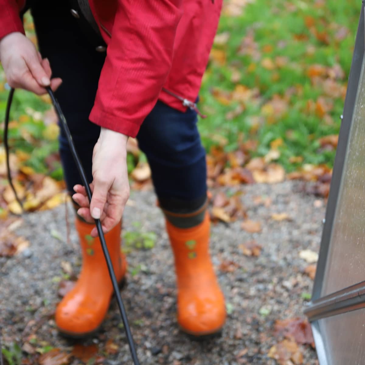 Oranssit kumisaappaat ja kädet vetämässä sähköjohtoa