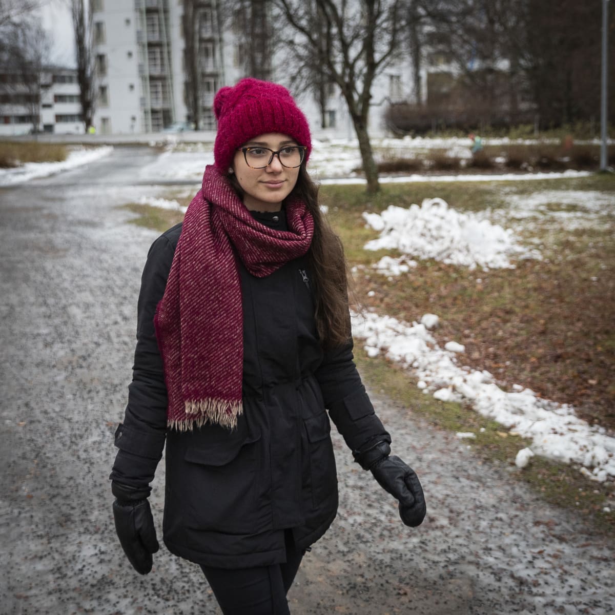 Nuori nainen kävelee puistossa talvivaatteet päällään.