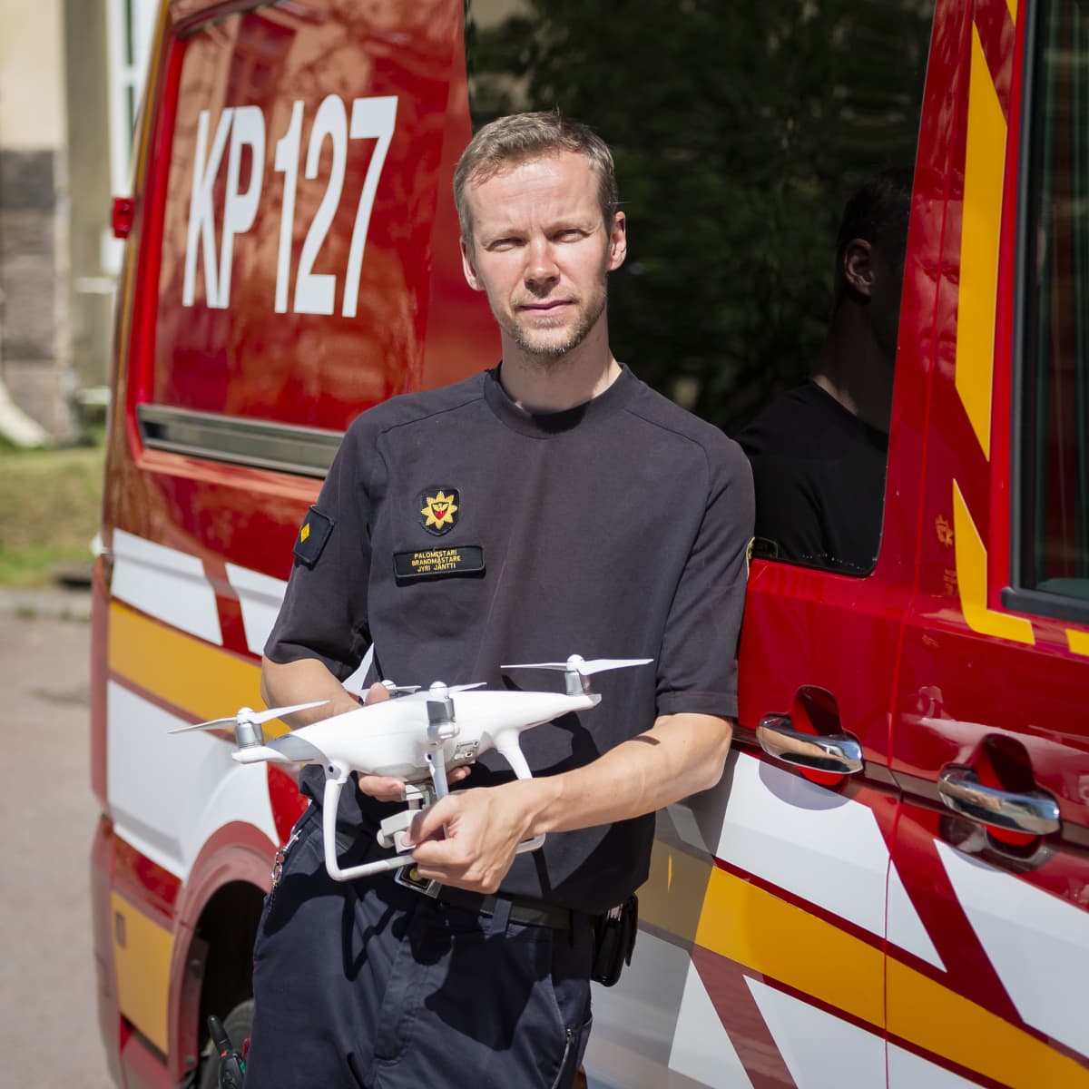 Jyri Jäntti nojaa paloautoon drooni käsissään.