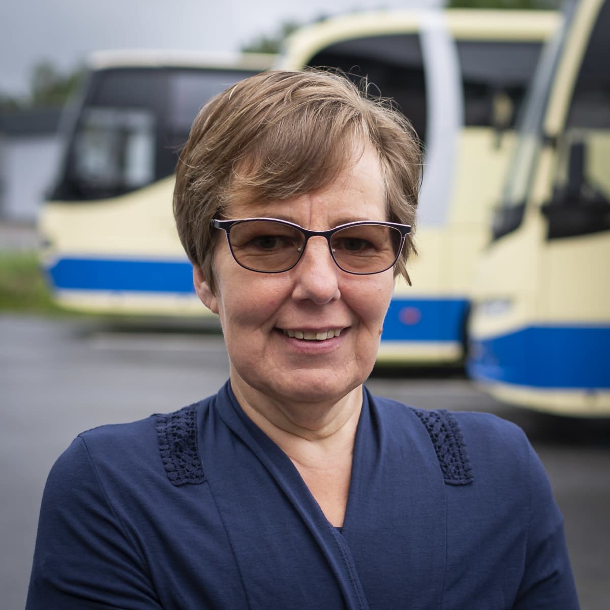 Eija Kangas ulkona. Taustalla näkyy linja-autoja.