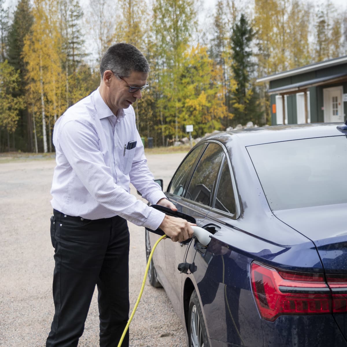 Hannu hautala laittaa latauspistokkeen sähköautoonsa.