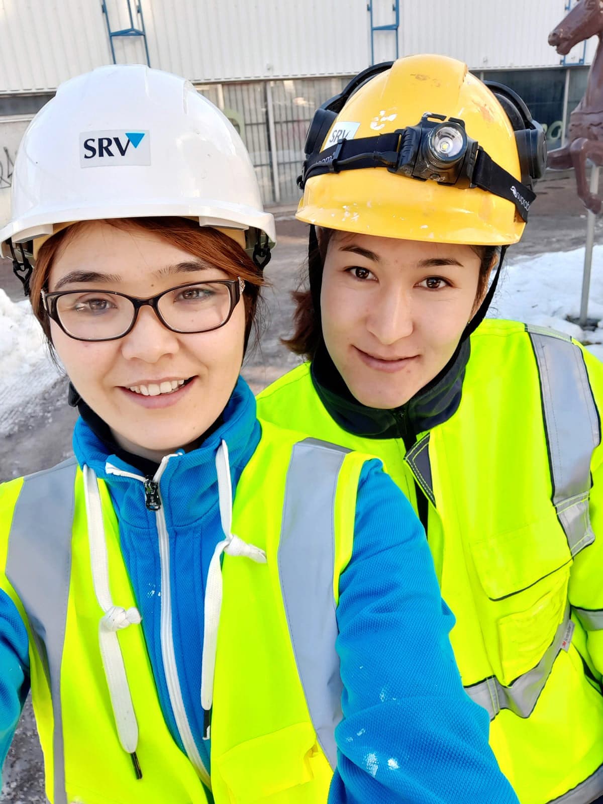 Kuvassa kaksi nuorta työmaakypärät ja työvaatteet päällään.
