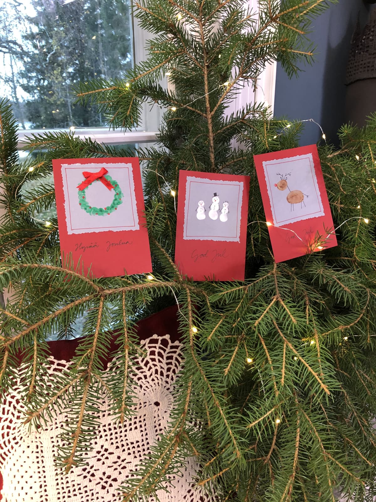 Kolme käsintehdyt joulukortit kuusenoksilla.