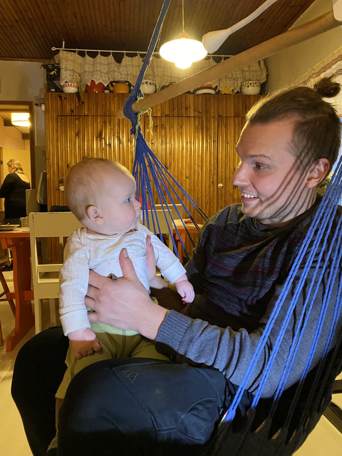 Aatos isä Antin sylissä sisällä talon tuvassa.