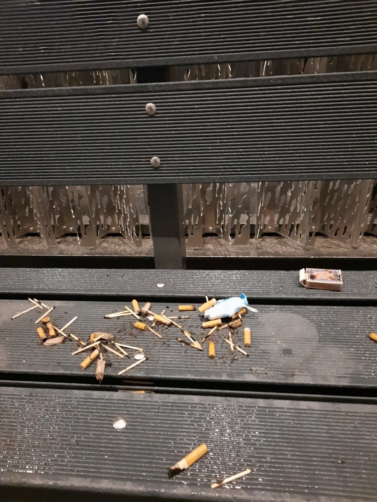Tupakan tumppeja ja tulitikkuja penkillä sairaalan edustalla.