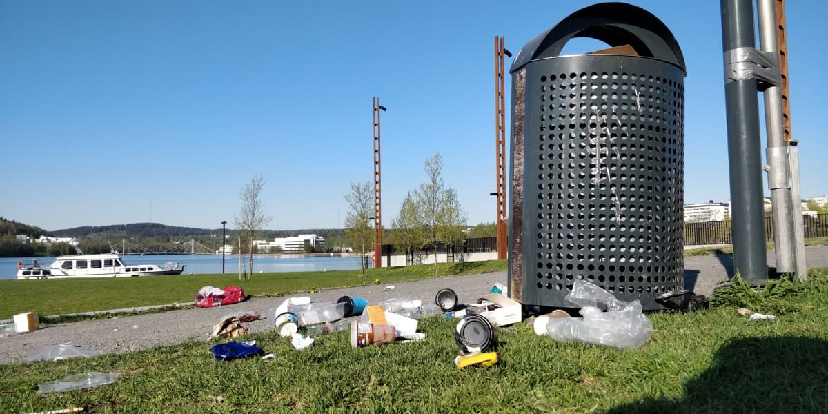 Roskia maassa roskiksen vieressä.