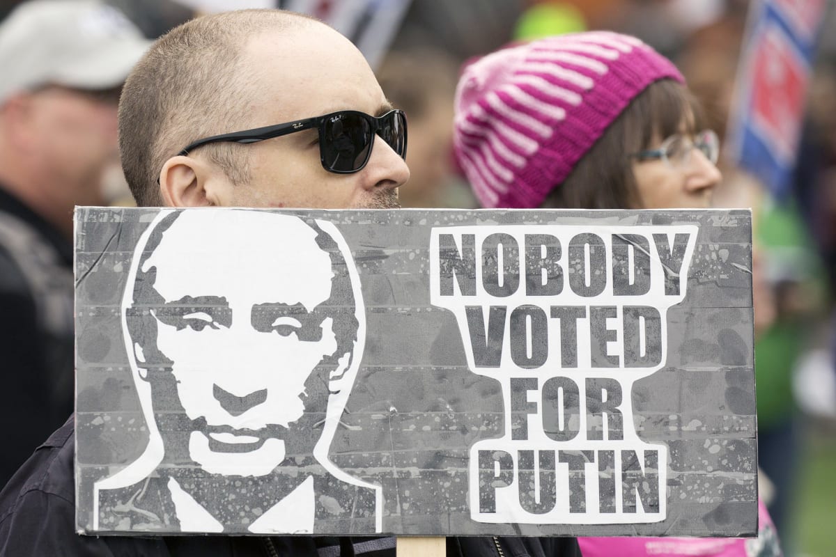 Mies kantaa Putinin vastaista kylttiä Trumpia vastaan osoitetussa mielenosoituksessa Washingtonissa .