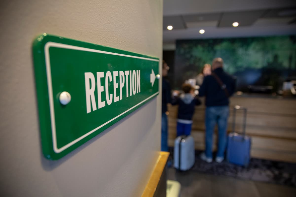 Kuva hotellivastaanoton vihreästä kyltistä, jossa lukee reception.