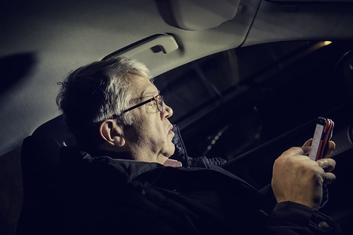 Juha Rehula istuu autossa pimeyden keskellä tutkien puhelintaan.