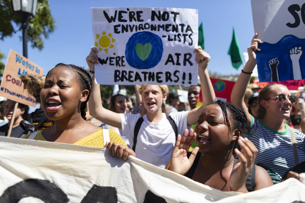 Mielenosoittajia, kyltissä lukee "We're not environmentalists, we're air breathers."
