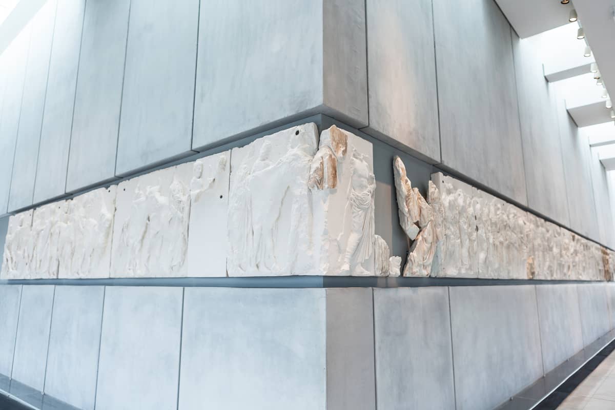 Parthenonin metrin korkuinen marmorifriisi kuvaa antiikin Panathenaia-juhlakulkuetta ratsumiehineen, juhlan osanottajineen ja uhrieläimineen. Valkoiset osat ovat Lontoon British Museumissa.