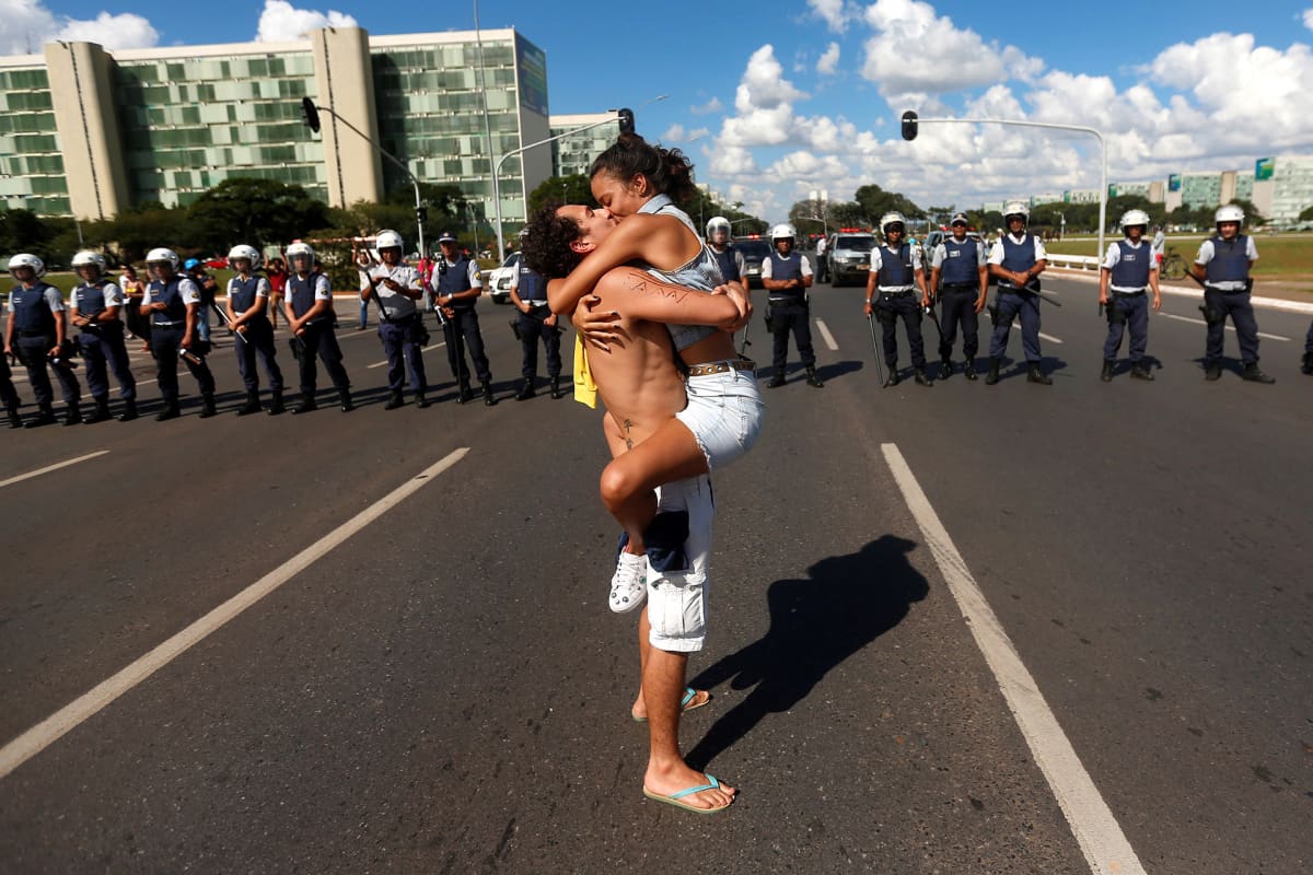 Nais- ja miesprotestoija suutelevat kiihkeästi poliisien edessä vastustaen Brasilian presidentti Jair Bolsonaron koulutusleikkauksia.
