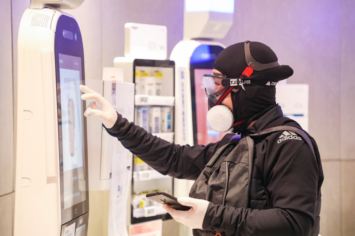 Täysin suojattu mies kaupan itsepalveluautomaatilla Wuhanissa.
