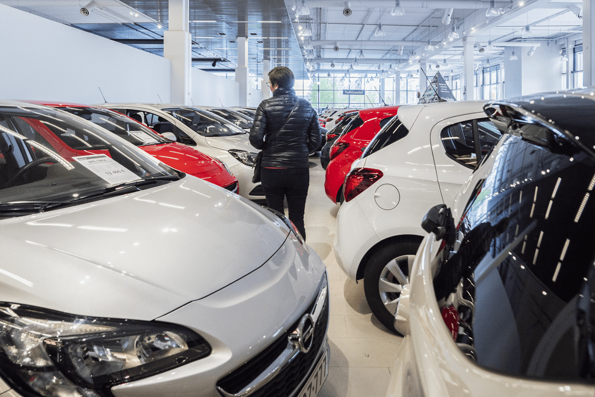 Nainen katselemassa käytettyjä autoja autoliikkeessä.