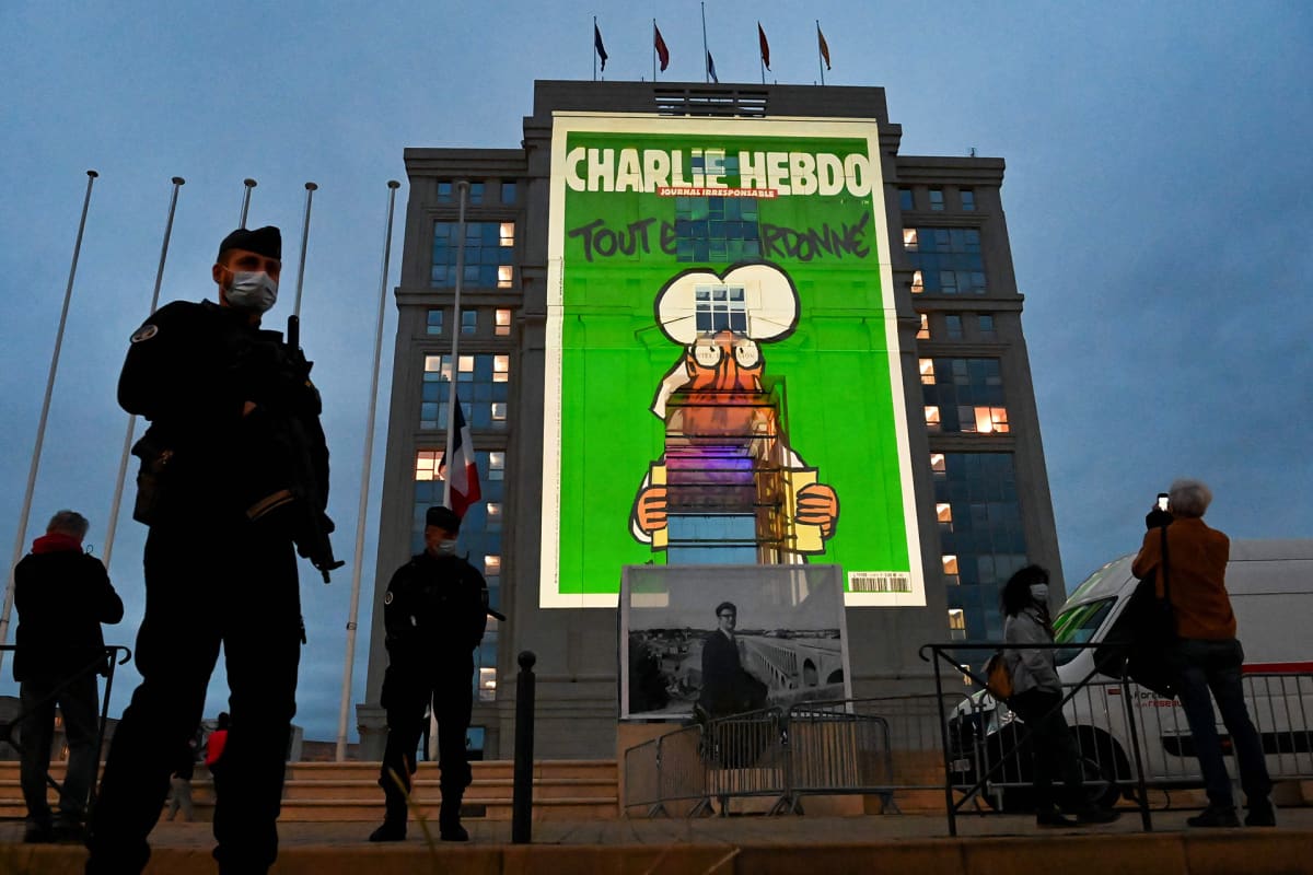 Aseistetut poliisit vartioivat Hotel de Regionin edustaa Montpellierissa kun rakennuksen julkisivuun heijastetaan Charlie Hebdon pilakuvia.