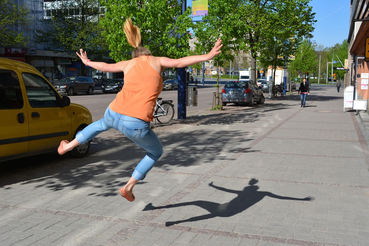 Nainen hyppää ilmaan kadulla.