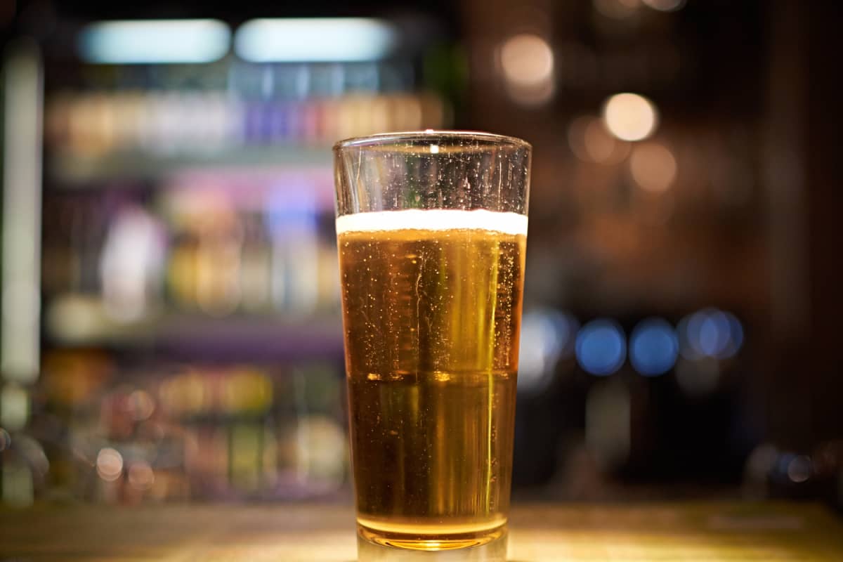 A glass of beer on a bar.
