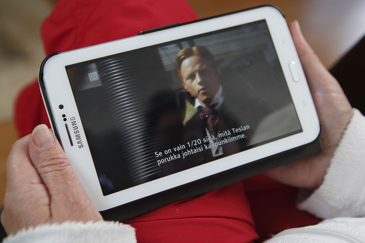 Nainen katselee televisiota älypuhelimella.