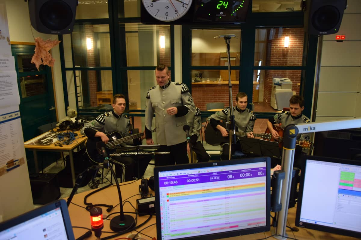 Viisi sotilasasuista soittajaa radion lähetysstudiosa.