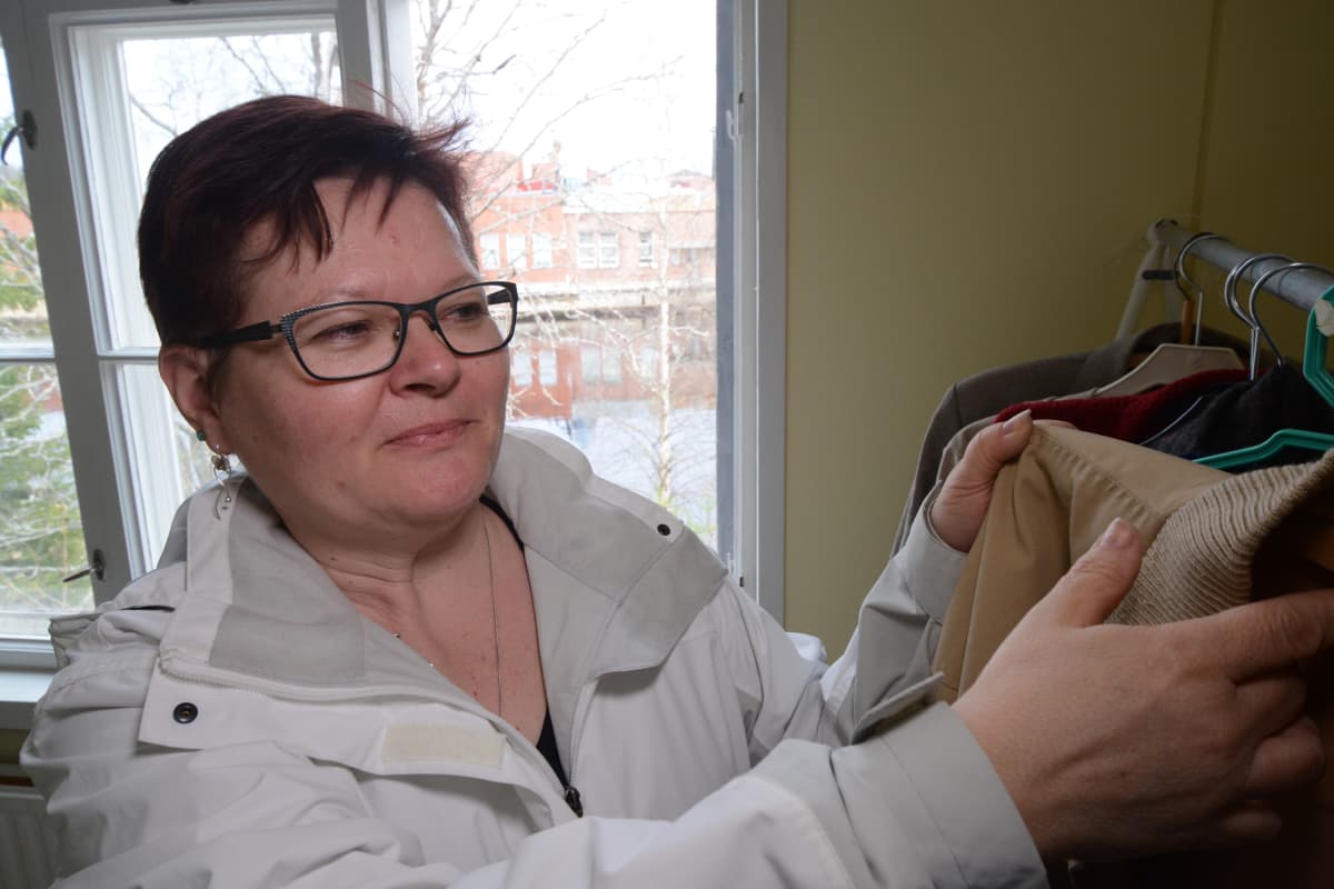 Tuula Roininen asettelee vanhoja vaatteita rekkiin.