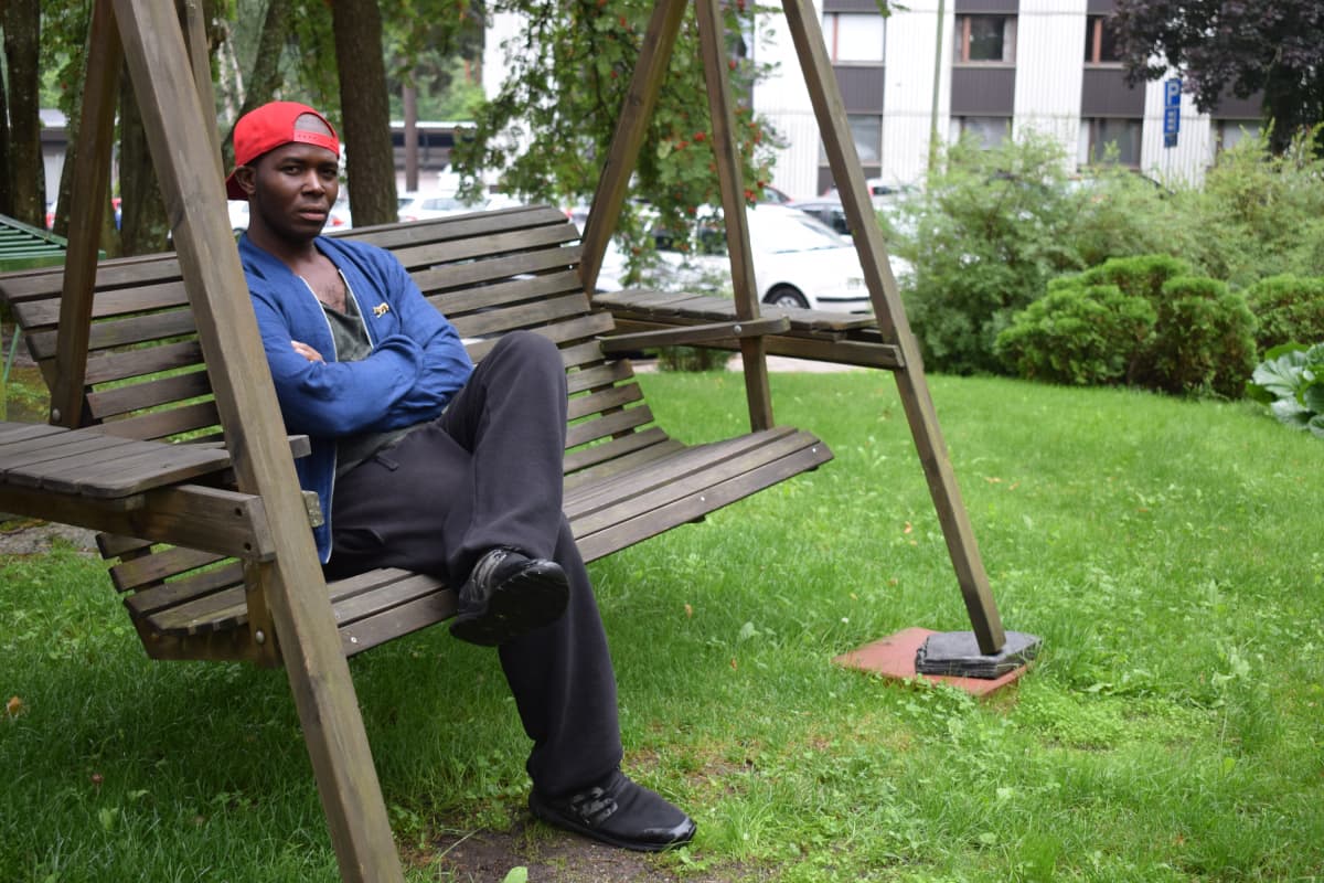tummaihoinen mies istuu mietteliäänä keinussa