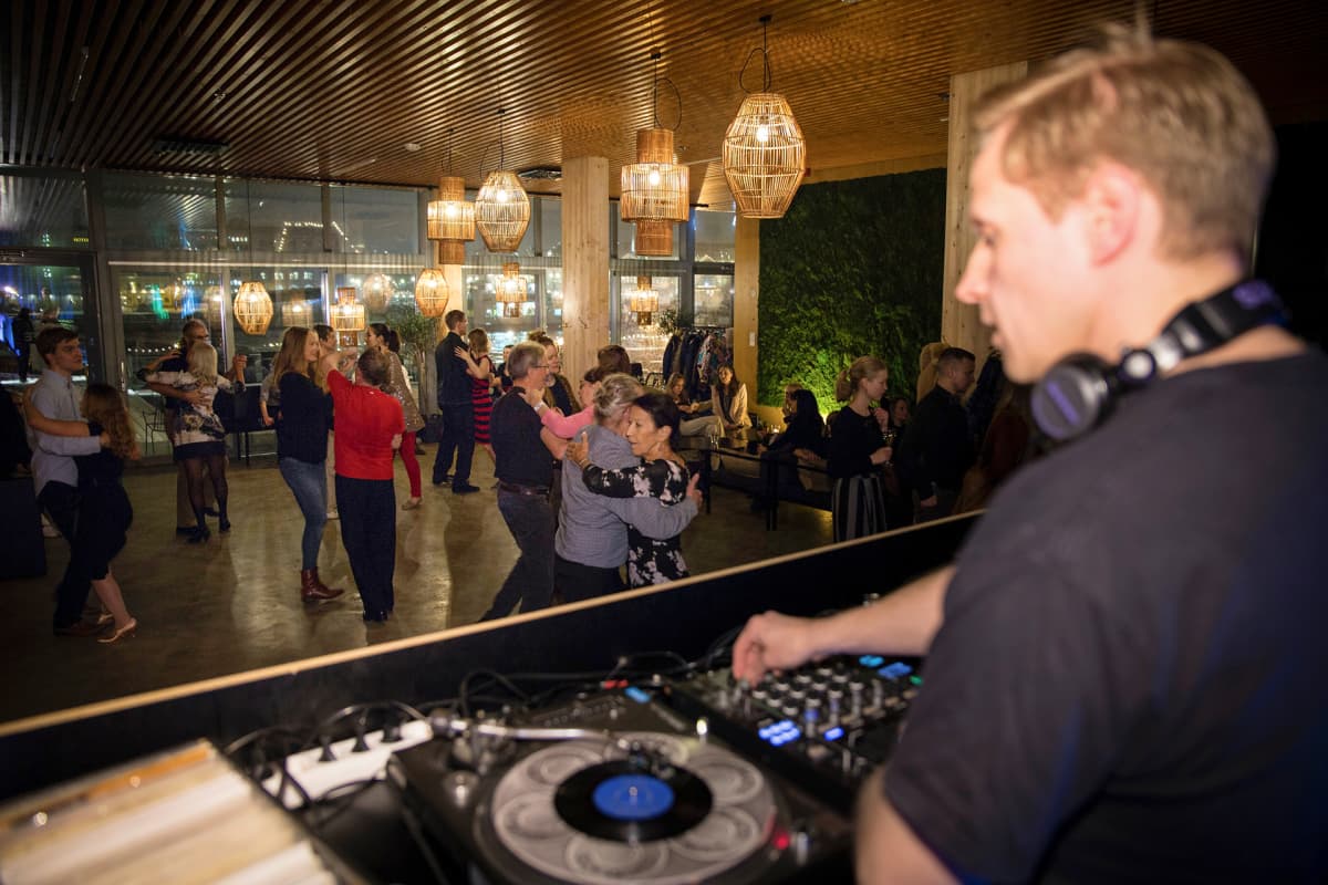DJ etualalla soittaa levyjä ja taustalla näkyy pareja tanssimassa.