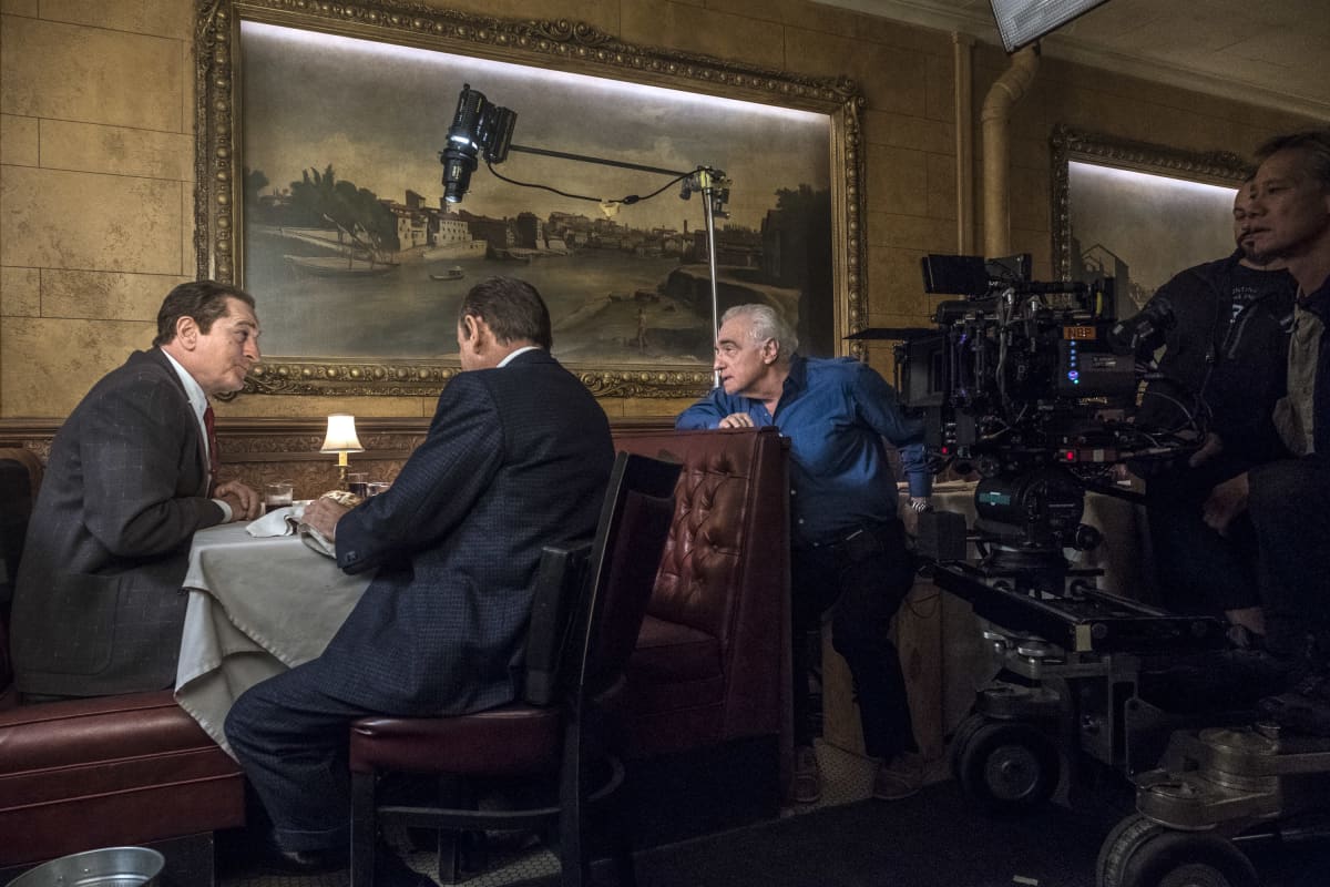 Inspelningsbild från The Irishman. Robert De Niro, en man som sitter med ryggen åt och regissören Martin Scorsese som ger order om hur han vill att nästa scen skall göras.
