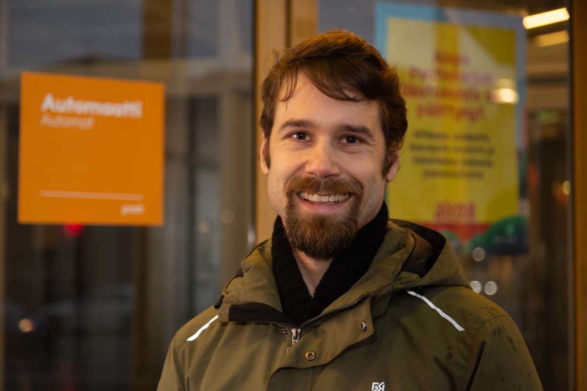 Tuomas Finne hymyilee Elävän musiikin yhdistyksen mahdollisen tulevan uuden kodin edessä kauppakeskus Puhoksen pihalla.
