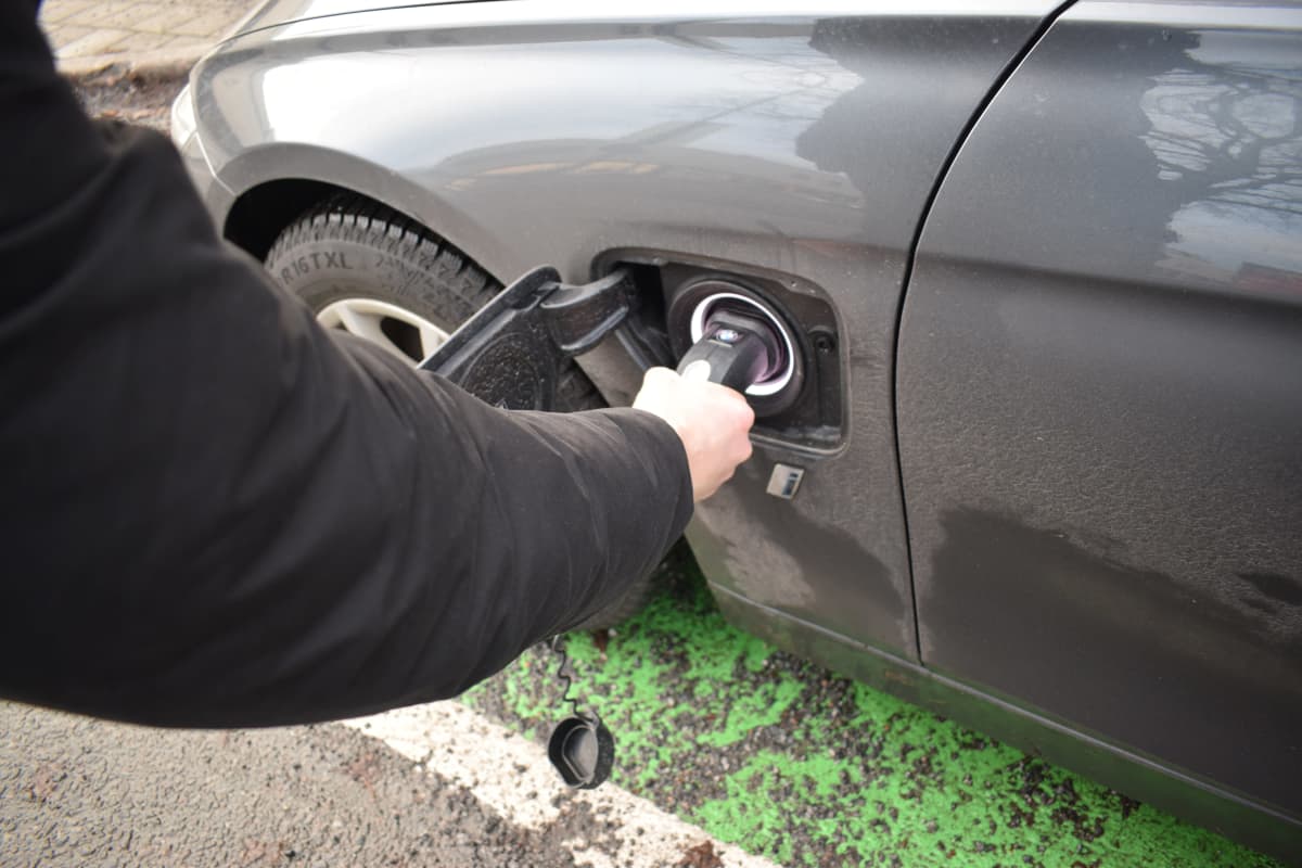 Mies kokeilee, että ladattavan hybridin kaapeli on kiinni.