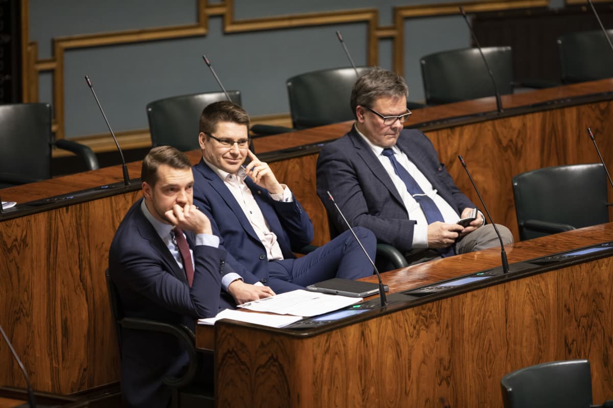 Tre riksdagsledamöter i rad i plenisalen. För nära, enligt coronabestämmelserna