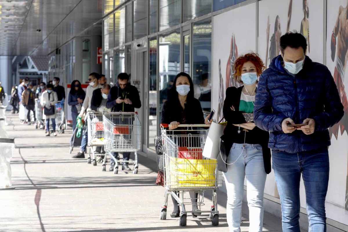 Asiakkaat odottivat hengityssuojaimet kasvoillaan ja turvavälit käytössä supermarkettiin ennen pääsiäistä Milanossa.