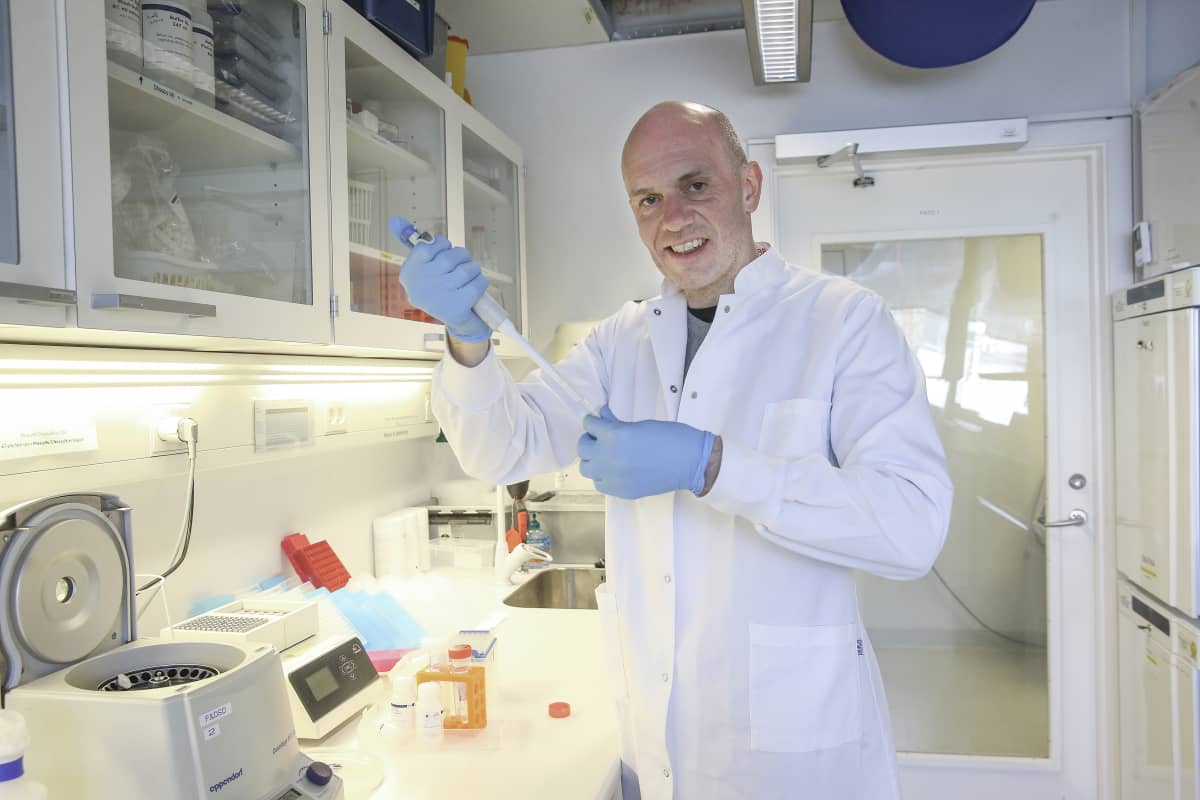 Valkotakkinen mies tekemässä virustestiä laboratoriossa.