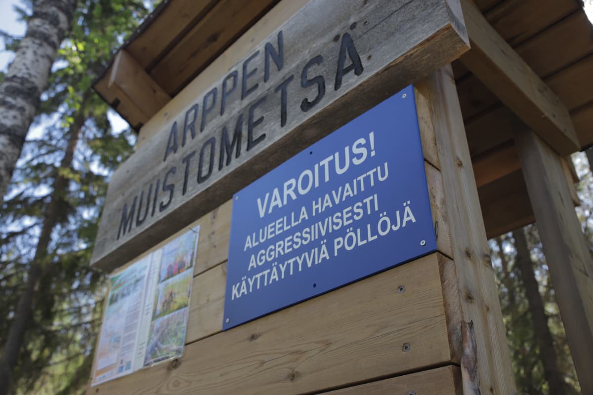 Arppen muistometsäkyltti, jonka alla lukee "varoitus! alueella havaittu aggressiivisesti käyttäytyviä pöllöjä".