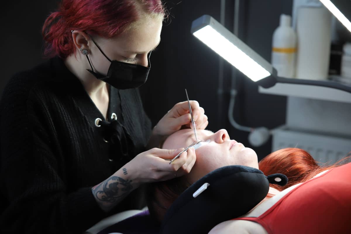 Carol Petrauskas laittamassa ystävälleen ripsienpidennyksiä Royal Beauty Pie -liikkeessä Kotkassa.