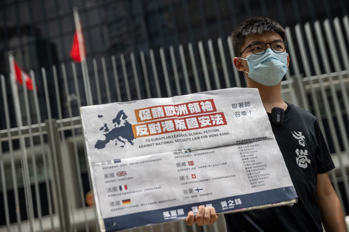 Joshua Wong pitää kädessään kiinankielistä plakaattia