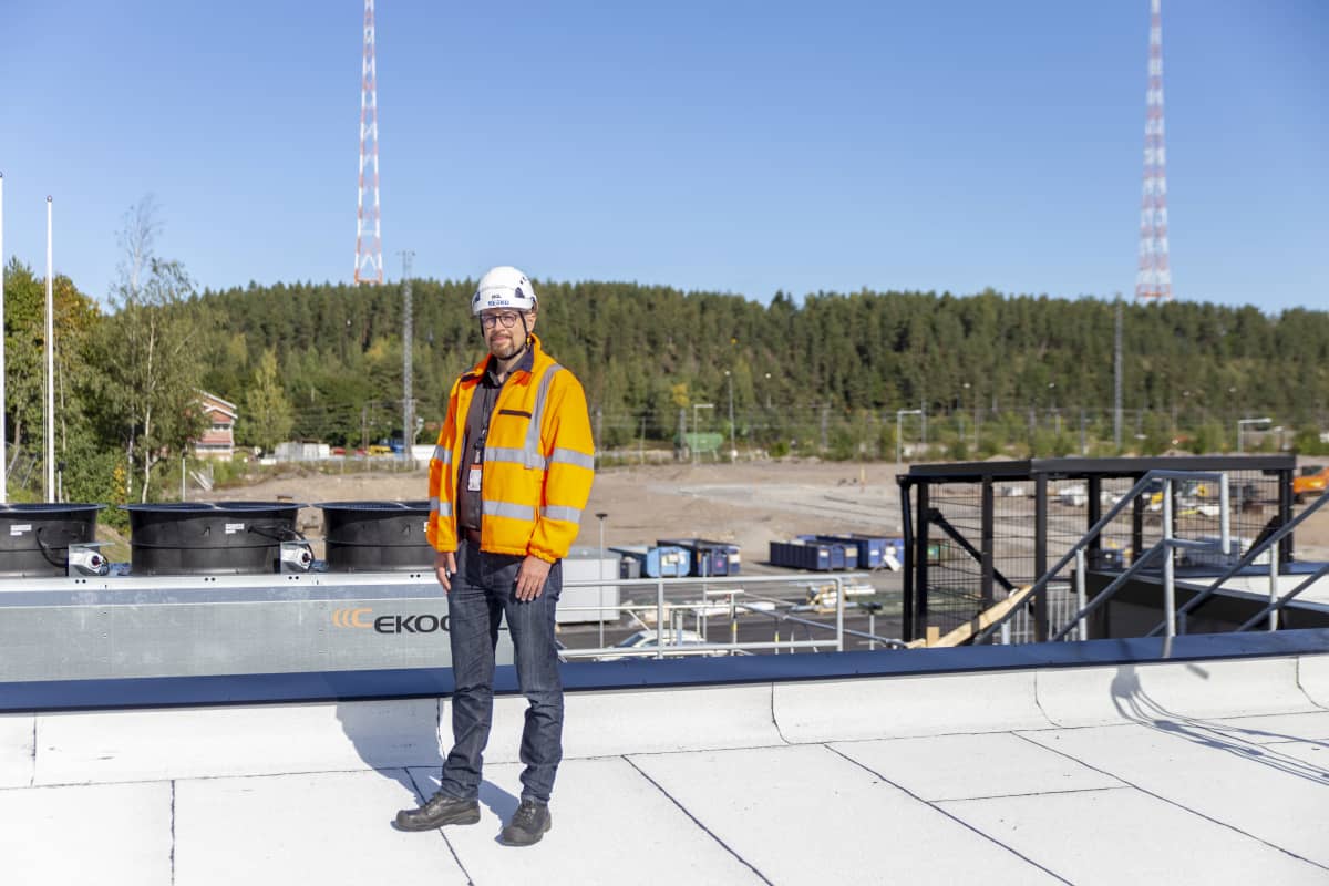 K-ryhmän talotekniikkapäällikkö Antti Kokkonen seisoo rakenteilla olevan Supermarketin katolla Lahdessa syyskuussa 2020. Taustalla näkyvät kuuluisat Lahden radiomastot. Taivas on pilvetön ja kuulaan sininen.