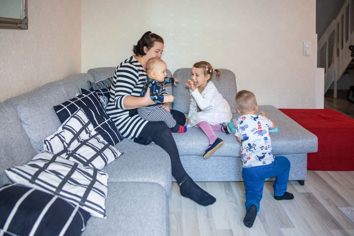 Sonja Kyrönlahti leikkii sohvalla lapsiensa Esterin, Eemelin ja Eetun kanssa.